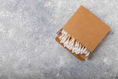Dokulu bir arka planda eko kraft ambalajında pamuk tomurcukları. Beyaz arka planda pamuklu çubuk. Burun ve kulaklarda hijyen çubukları. Bambu pamuk tomurcukları. Eko-dost. Mesaj için yer. Kopya için yer..