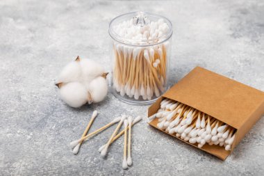 Dokulu bir arka planda eko kraft ambalajında pamuk tomurcukları. Beyaz arka planda pamuklu çubuk. Burun ve kulaklarda hijyen çubukları. Bambu pamuk tomurcukları. Eko-dost. Mesaj için yer. Kopya için yer..