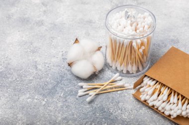 Dokulu bir arka planda eko kraft ambalajında pamuk tomurcukları. Beyaz arka planda pamuklu çubuk. Burun ve kulaklarda hijyen çubukları. Bambu pamuk tomurcukları. Eko-dost. Mesaj için yer. Kopya için yer..