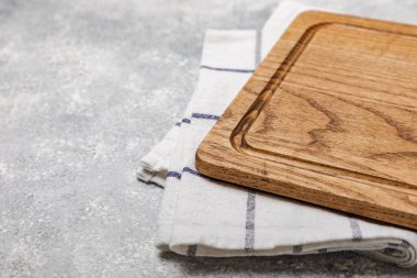 Mutfak havlusunun üzerinden tahta kesmek mutfak masası dokusu arka planında. Yemek tarifi. Mutfak eşyaları. Boş, modern tahta kesme tahtası. Menü. - Model. Mesaj için yer. Kopyalanacak yer.