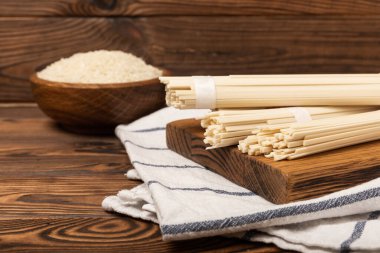 Kahverengi desenli ahşap arka planda pirinç eriştesi. Çiğ funselli erişte ve pilav. Tayland usulü kurutulmuş erişte. Mesaj için yer. Kopyalanacak yer. Yakın plan..