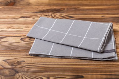 Kareli mutfak pamuk havluları kahverengi bir doku masasının üzerine katlanmış. Mutfak eşyaları. Mutfak havlusu veya tekstil peçetesi. Uzayı metin için kopyala. Mesaj için yer. Masa örtüsü.