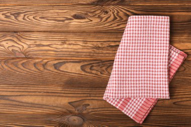 Kareli mutfak pamuk havluları kahverengi bir doku masasının üzerine katlanmış. Mutfak eşyaları. Mutfak havlusu veya tekstil peçetesi. Uzayı metin için kopyala. Mesaj için yer. Masa örtüsü.