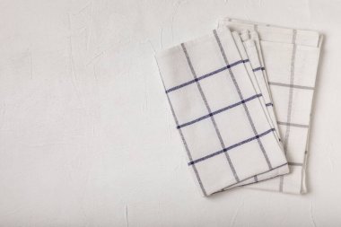 Beyaz desenli bir masanın üzerine katlanmış basit desenli mutfak pamuk havluları. Mutfak eşyaları. Mutfak havlusu veya tekstil peçetesi. Uzayı metin için kopyala. Mesaj için yer. Masa örtüsü.