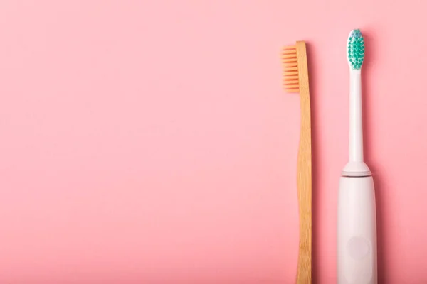 stock image electric toothbrush, bamboo and handmade toothbrushes on a pink background with copy space. Flat lay. Oral hygiene. Oral care kit. Dentist concept. Place for text. Place to copy.