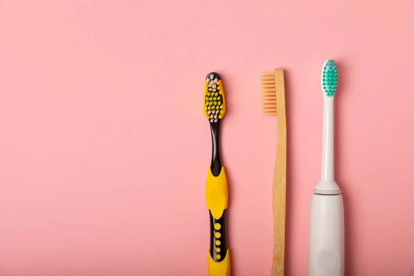 electric toothbrush, bamboo and handmade toothbrushes on a pink background with copy space. Flat lay. Oral hygiene. Oral care kit. Dentist concept. Place for text. Place to copy.