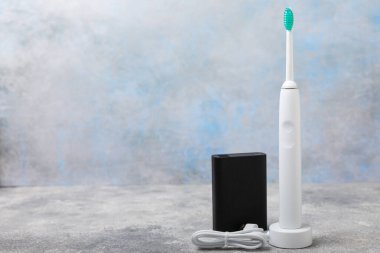Modern bir elektrikli diş fırçası mermer zemin üzerinde dış güç bankasının bataryasından şarj ediliyor. Modern ev teknolojisi konsepti. Ağız ve sakız bakımı. Tıp konsepti. Dişçi.
