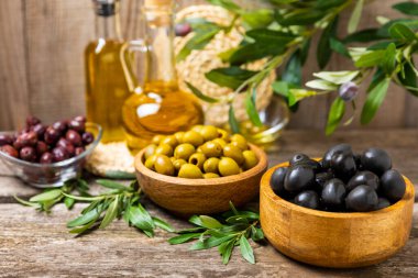 Eski ahşap bir arka planda yeşil, siyah ve kırmızı zeytinlerin yaprakları var. Lezzetli ve sağlıklı yiyecekler. Lezzetli. Akdeniz mutfağı. Mesaj için yer. kopyalama alanı.