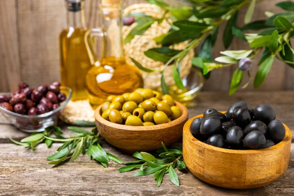Green, black and red olives with leaves in bowls on a textured old wood background. Delicious and healthy food. Delicacy.Mediterranean Kitchen. Place for text. copyspace.