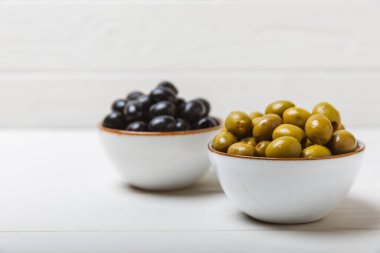 Dokulu arka planda yeşil ve siyah zeytin. Farklı türde zeytin ve taze zeytin yapraklı zeytin yağları. Lezzetli. Akdeniz mutfağı. Boşluğu kopyala.