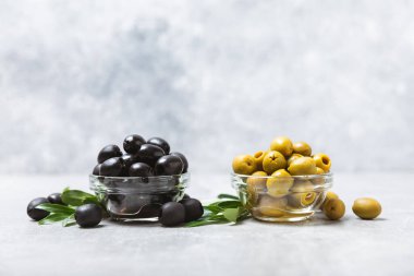 Dokulu arka planda yeşil ve siyah zeytin. Farklı türde zeytin ve taze zeytin yapraklı zeytin yağları. Lezzetli. Akdeniz mutfağı. Boşluğu kopyala.