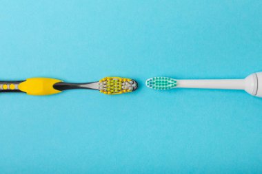 Mavi arka planda elektrikli ve manuel diş fırçaları. Yukarıdan bak. Ağız temizliği. Sıradan diş fırçası, eko ve elektrikli diş fırçası. Ağız temizliği. Ağız bakım kiti. Dişçi konsepti. Diş bakımı. 