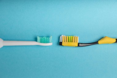 Mavi arka planda elektrikli ve manuel diş fırçaları. Yukarıdan bak. Ağız temizliği. Sıradan diş fırçası, eko ve elektrikli diş fırçası. Ağız temizliği. Ağız bakım kiti. Dişçi konsepti. Diş bakımı. 