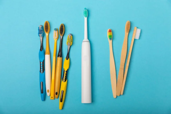 Electric and manual toothbrushes on a blue background. View from above. Oral hygiene. Ordinary toothbrush, eco and electric toothbrush. Oral hygiene. Oral Care Kit. Dentist concept. Dental care.