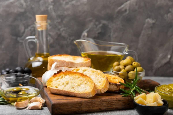 stock image Ciabattas, olive oil in a bowl with olives, herbs, spices, garlic, pesto, parmesan and ciabatta bread on a texture background.Banner. Healthy food concept.Delicacy. Mediterranean Kitchen. Copy space.