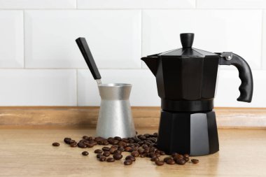 Mutfağın arka planında moka kabı var. Masasında sıcak kokulu kahve olan kahve makinesi. Mesaj için yer. Boşluğu kopyala