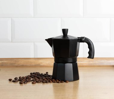 Mutfağın arka planında moka kabı var. Masasında sıcak kokulu kahve olan kahve makinesi. Mesaj için yer. Boşluğu kopyala