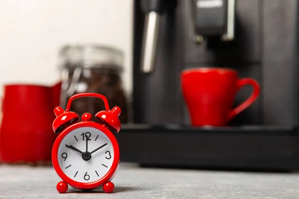 Ébresztőóra Kávéfőző Hátterében Piros Ébresztőóra Konyhaasztalon Háttérben Egy Csésze Aromás — Stock Fotó