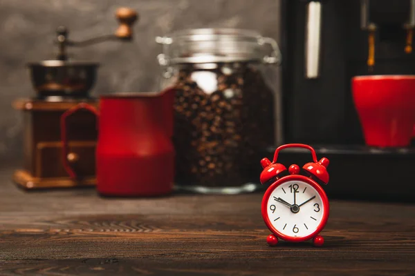 Ébresztőóra Kávéfőző Hátterében Piros Ébresztőóra Konyhaasztalon Háttérben Egy Csésze Aromás — Stock Fotó