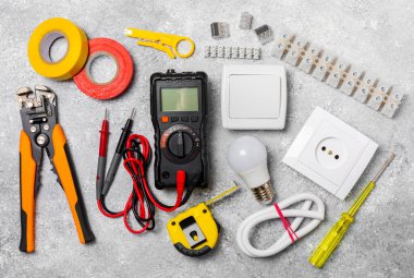 Mermer zemin üzerinde mermer arkaplan üzerinde elektrikli ekipman. Üst görünüm. Elektrik aracı seti. Çoklu metre, test cihazı, tornavida, kesiciler, koli bandı, lamba, mezura, mezura ve kablo..