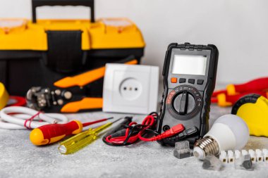 Mermer zemin üzerinde mermer arkaplan üzerinde elektrikli ekipman. Üst görünüm. Elektrik aracı seti. Çoklu metre, test cihazı, tornavida, kesiciler, koli bandı, lamba, mezura, mezura ve kablo..