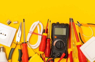Sarı zemin üzerindeki elektrik teçhizatı kopya alanı ile üst görünüm. Elektrik aracı seti. Çoklu metre, testçi, tornavida, kesiciler, koli bandı, lamba, mezura, mezura ve kablo..