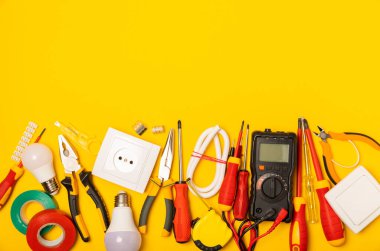 Sarı zemin üzerindeki elektrik teçhizatı kopya alanı ile üst görünüm. Elektrik aracı seti. Çoklu metre, testçi, tornavida, kesiciler, koli bandı, lamba, mezura, mezura ve kablo..