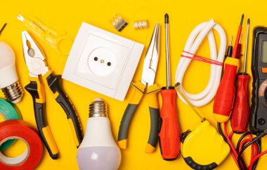 Sarı zemin üzerindeki elektrik teçhizatı kopya alanı ile üst görünüm. Elektrik aracı seti. Çoklu metre, testçi, tornavida, kesiciler, koli bandı, lamba, mezura, mezura ve kablo..