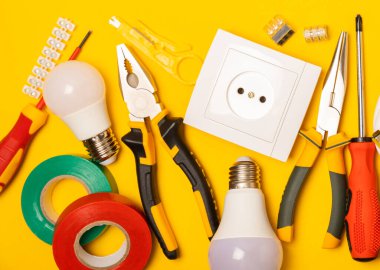 Sarı zemin üzerindeki elektrik teçhizatı kopya alanı ile üst görünüm. Elektrik aracı seti. Çoklu metre, testçi, tornavida, kesiciler, koli bandı, lamba, mezura, mezura ve kablo..