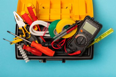 Mavi arka planda kopyalanmış elektrik teçhizatı. Üst görünüm. Elektrik aracı seti. Çoklu metre, test cihazı, tornavida, kesici, koli bandı, lamba, mezura, mezura ve kablo..