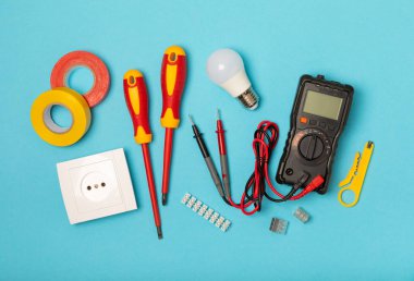 Mavi arka planda kopyalanmış elektrik teçhizatı. Üst görünüm. Elektrik aracı seti. Çoklu metre, test cihazı, tornavida, kesici, koli bandı, lamba, mezura, mezura ve kablo..