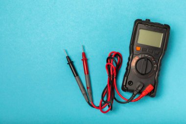 Mavi arka planda kopyalanmış elektrik teçhizatı. Üst görünüm. Elektrik aracı seti. Çoklu metre, test cihazı, tornavida, kesici, koli bandı, lamba, mezura, mezura ve kablo..