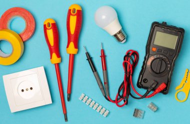 Mavi arka planda kopyalanmış elektrik teçhizatı. Üst görünüm. Elektrik aracı seti. Çoklu metre, test cihazı, tornavida, kesici, koli bandı, lamba, mezura, mezura ve kablo..