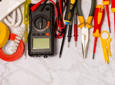 Mermer zemin üzerinde mermer arkaplan üzerinde elektrikli ekipman. Üst görünüm. Elektrik aracı seti. Çoklu metre, test cihazı, tornavida, kesiciler, koli bandı, lamba, mezura, mezura ve kablo..