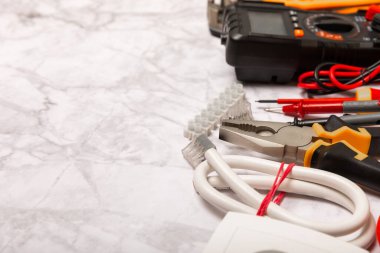 Mermer zemin üzerinde mermer arkaplan üzerinde elektrikli ekipman. Üst görünüm. Elektrik aracı seti. Çoklu metre, test cihazı, tornavida, kesiciler, koli bandı, lamba, mezura, mezura ve kablo..