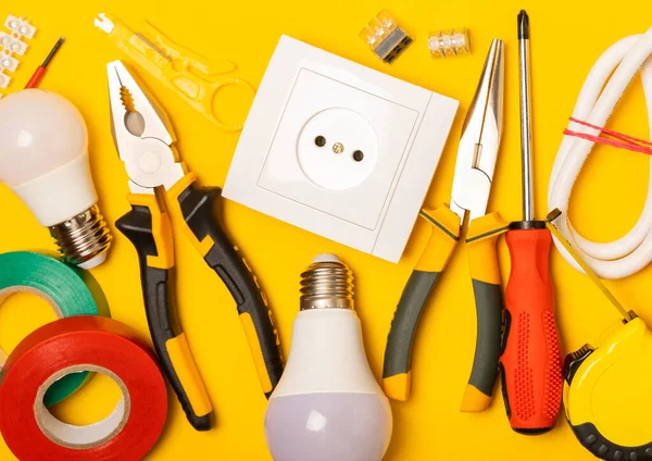 Sarı zemin üzerindeki elektrik teçhizatı kopya alanı ile üst görünüm. Elektrik aracı seti. Çoklu metre, testçi, tornavida, kesiciler, koli bandı, lamba, mezura, mezura ve kablo..