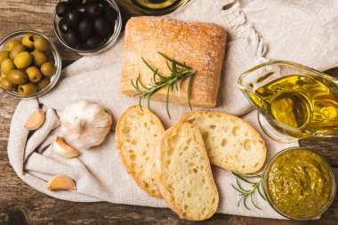 Bitkilerle, zeytinlerle, pesto sosuyla, sarımsak ve parmesanlı peynirle dilimlenmiş İtalyan ciabatta ekmeği. Taze ev yapımı İtalyan Ciabatta ekmeği. Bitki ve baharatla dilimlenmiş. Yazı için bir yer. kopyalama alanı.