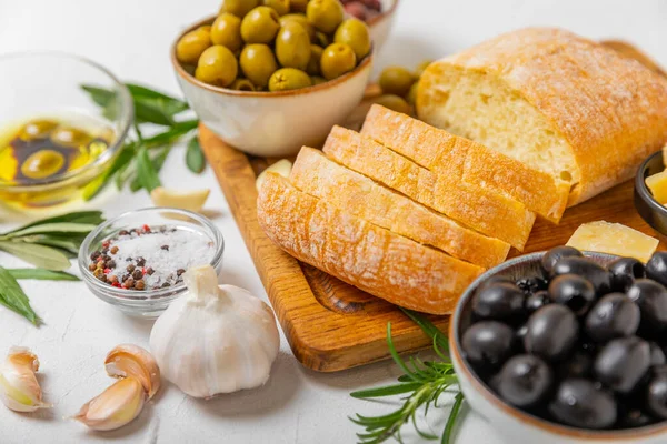 stock image Italian ciabatta bread cut in slices with herbs, olives, pesto sauce, garlic and parmesan cheese on a concrete table. Fresh homemade Italian Ciabatta bread sliced with herbs and spices.Place for text. copyspace.