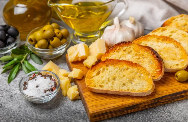 stock image Italian ciabatta bread cut in slices with herbs, olives, pesto sauce, garlic and parmesan cheese on a concrete table. Fresh homemade Italian Ciabatta bread sliced with herbs and spices.Place for text. copyspace.