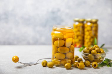 Beton bir arka planda cam kavanozda zeytinler. Kavanozda yeşil zeytin. Cam kavanozda turşulu zeytin. Ahşap bir arka planda. Salamura zeytin. Mesaj için yer var. Kopya için yer var. Vejetaryen yemeği.