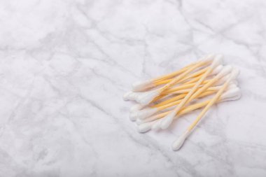 Beyaz mermer zeminde pamuk tomurcukları. Pamuklu bez. Temiz pamuk tomurcukları. Hijyen ürünleri. Kulak çubukları. Mesaj için yer. Kopyalanacak yer. Yakın plan. Düz yatıyordu.