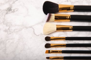 Beyaz mermer arka planda kozmetik makyaj fırçası. Profesyonel makyaj fırçaları. Göz farı, kızarıklık, temel ve dış hatlı fırçalar. Makyaj aleti. Vizeci. Metin için yer. Boşluğu kopyala