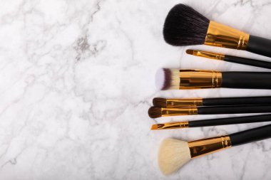 Beyaz mermer arka planda kozmetik makyaj fırçası. Profesyonel makyaj fırçaları. Göz farı, kızarıklık, temel ve dış hatlı fırçalar. Makyaj aleti. Vizeci. Metin için yer. Boşluğu kopyala