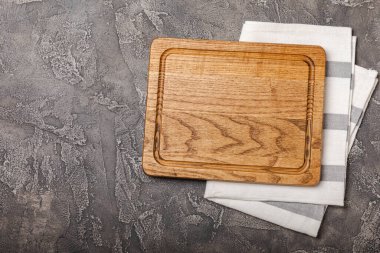 Mutfak masasının üzerinde boş ahşap tahta var. Mutfak havlusuyla tahta kesmek. Tahta kesme tahtası, kopyalama alanı. Mutfak eşyaları. Yemek tarifi. Mesaj için yer. Düz yatıyordu.