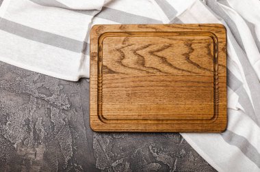 Mutfak masasının üzerinde boş ahşap tahta var. Mutfak havlusuyla tahta kesmek. Tahta kesme tahtası, kopyalama alanı. Mutfak eşyaları. Yemek tarifi. Mesaj için yer. Düz yatıyordu.