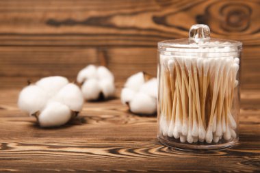 Kahverengi ahşap arka planda beyaz pamuklu çubuklar. Pamuk tomurcukları. Bambu pamuk tomurcukları. Çevre dostu. Kulaklar için hijyenik pamuklu bez. Mesaj için yer. Kopyalanacak yer.