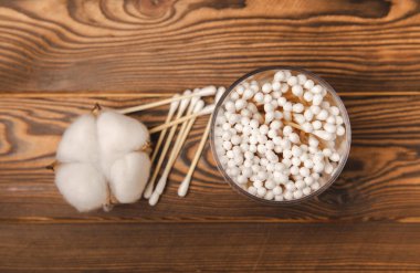 Kahverengi ahşap arka planda beyaz pamuklu çubuklar. Pamuk tomurcukları. Bambu pamuk tomurcukları. Çevre dostu. Kulaklar için hijyenik pamuklu bez. Mesaj için yer. Kopyalanacak yer.