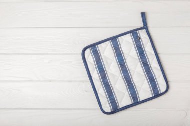 Mutfak eşyaları. Fırın eldiveni ve tutacağı beyaz desenli ahşap üzerinde sıcak tabaklar için. Yakın plan. Mesaj için yer. Boşluğu kopyala.