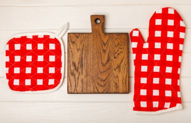 Mutfak eşyaları. Beyaz ahşap arka planda sıcak yemekler için fırın eldiveni ve tencere tutacağı. Yakın plan. Mesaj için yer. Boşluğu kopyala.