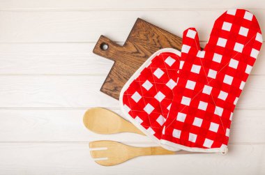 Mutfak eşyaları. Beyaz ahşap arka planda sıcak yemekler için fırın eldiveni ve tencere tutacağı. Yakın plan. Mesaj için yer. Boşluğu kopyala.